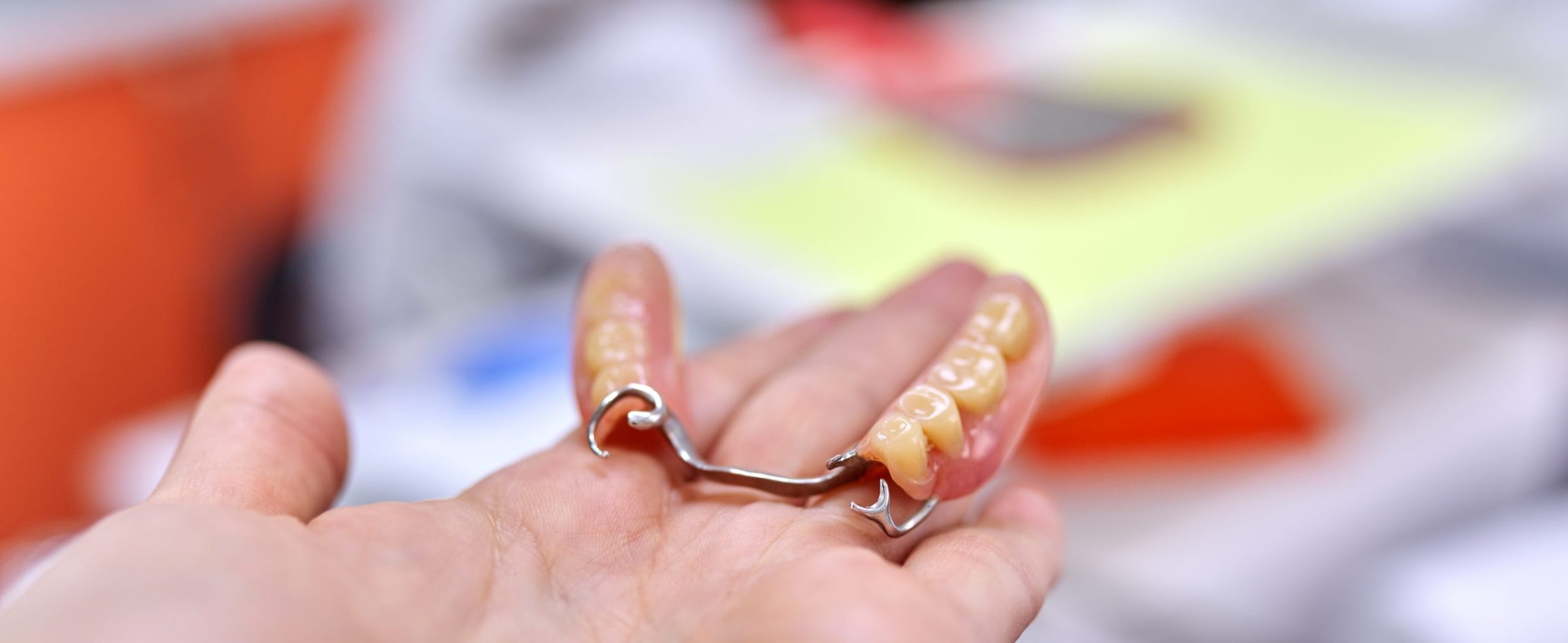 Dental implant model dental bridge in hand, dentist office background, concept of orthopedics, prosthetics, dentistry