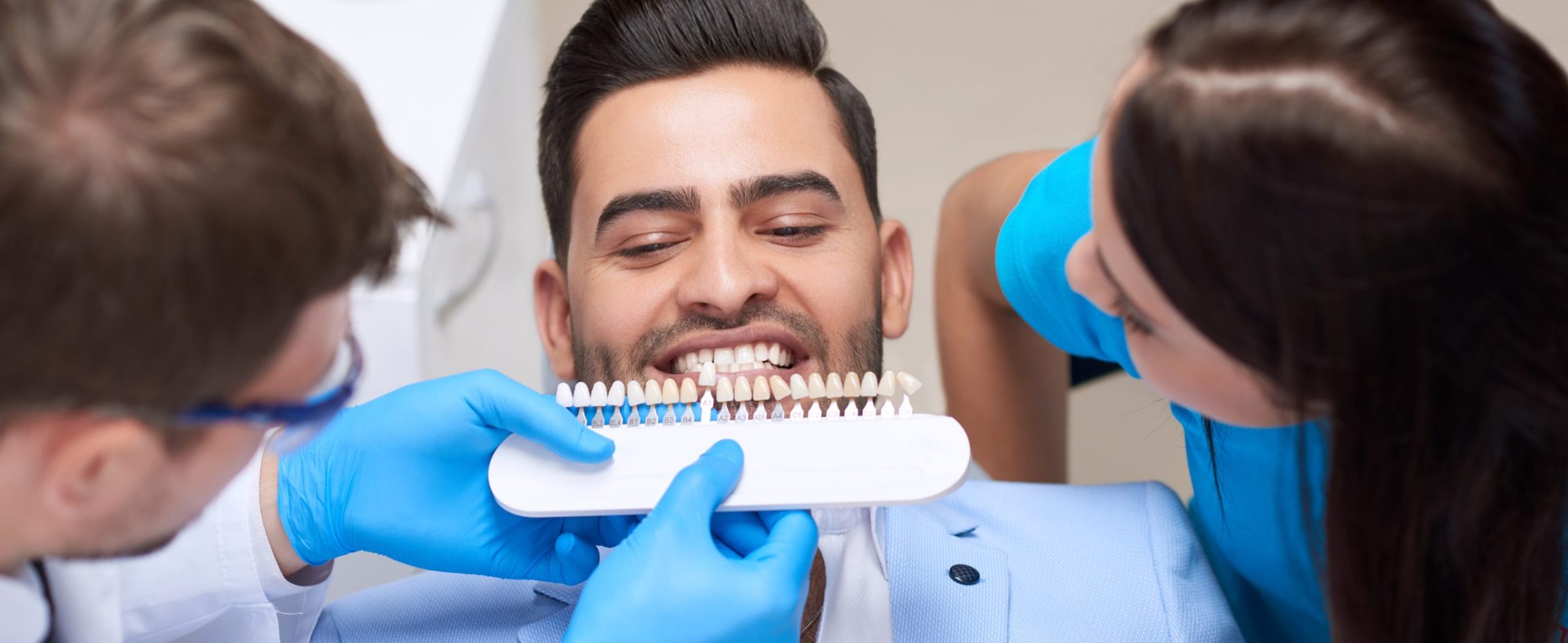 Top view shot of a profesisonal dentist wirking with assistance of the nurse choosing perfect matching color of implants for his male patient teeth medicine healthcare whitening dentures.